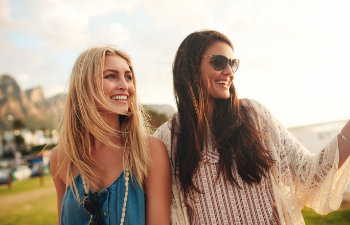 Two young happy women with perfect smiles having a walk.
