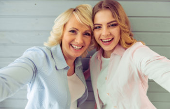 A happy teenage girl with her mother taking selfie.