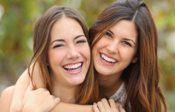 Two cheerful young women with perfect smiles.