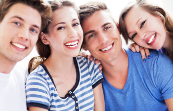 Group of four teenagers with perfect smiles.