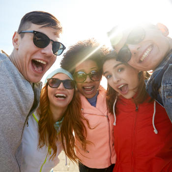 A multicultural group of happy young people wearing hoodies and sunglasses.