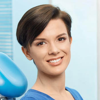 A young woman with a perfect smile sitting in a dental chair.