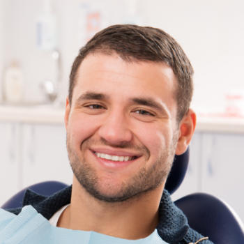 A young man with a perfect smile sitting in a dental chair.