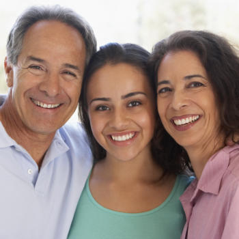 Portrait of broadly smiling Hispanic teenage girl with her mother and father.