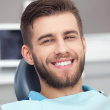 A young man with a perfect smile sitting in a dental chair.