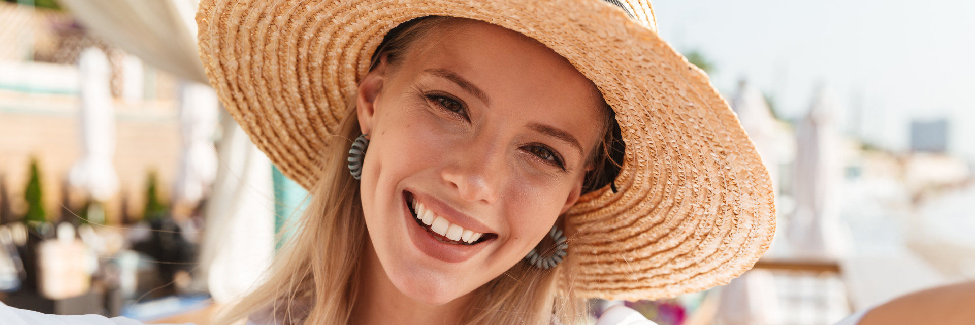 A beautiful young woman with a perfect smile wearing a straw hat.
