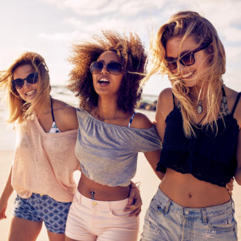 Three young happy women with perfect smiles spending a day on a beach.