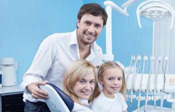 Smiling parents with a little daughter at a dental office.