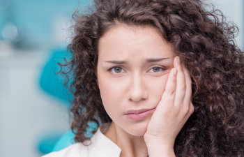 young woman holds her jaw with pain