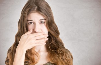 Female covering her mouth with her hand, isolated in white